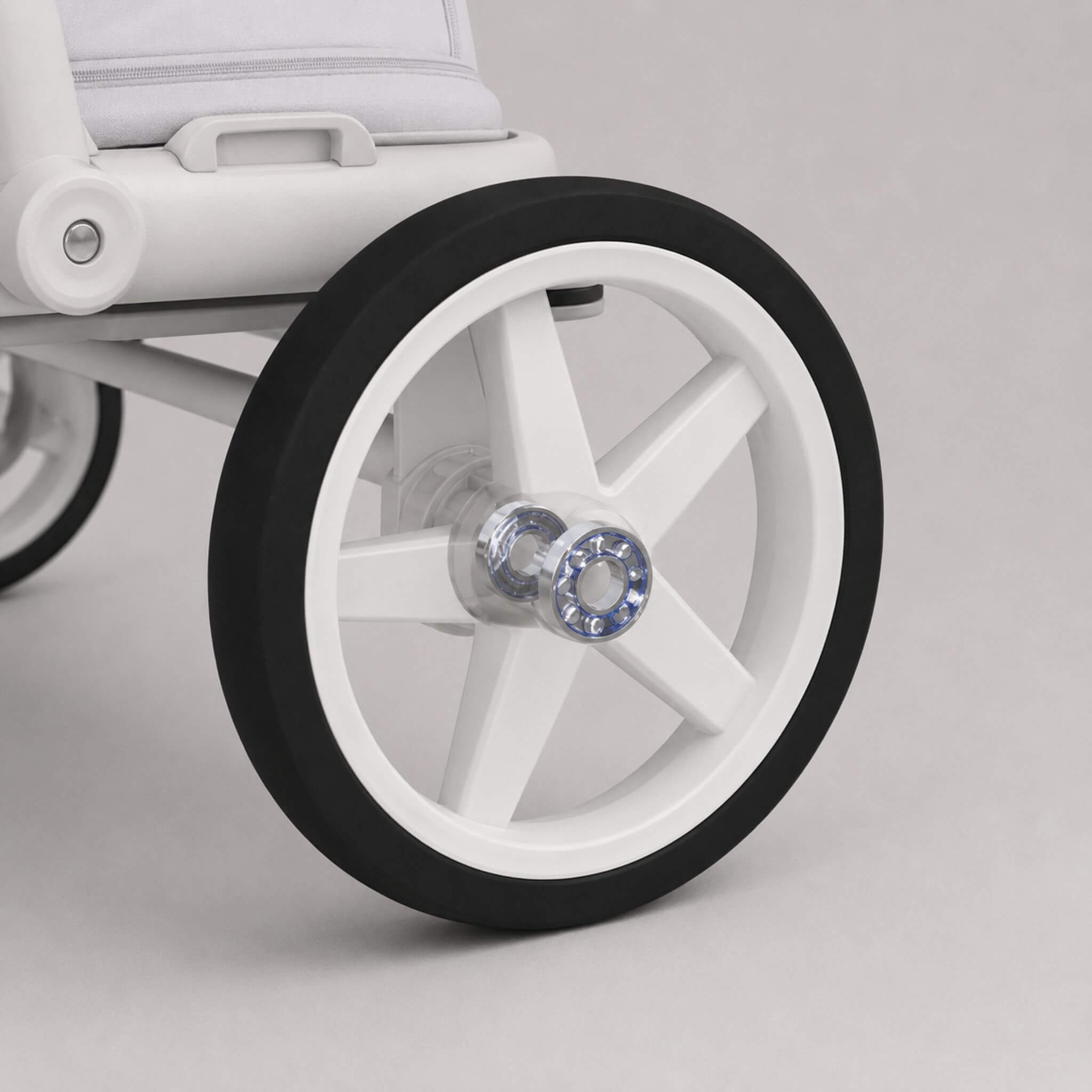 Close-up of a white stroller wheel with a black rubber tire and a clear central hub, shown on a light gray studio background.