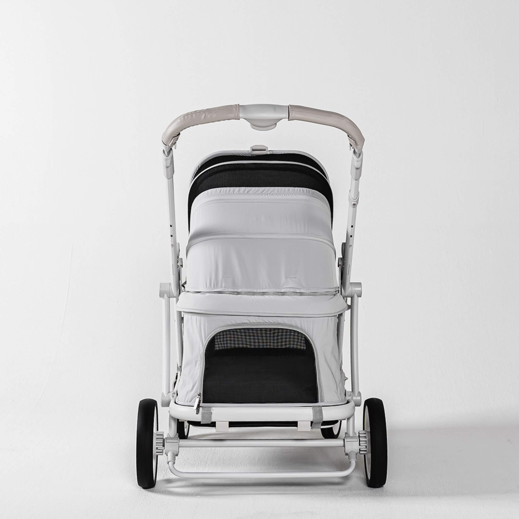 A modern stroller with a white and black canopy, a light gray padded seat cover, and a white frame with black wheels, photographed against a seamless white studio background.