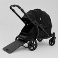 A black pet stroller with a matching black pet bed, black handlebar, and four wheels, shown on a light gray studio background with the front ramp lowered.