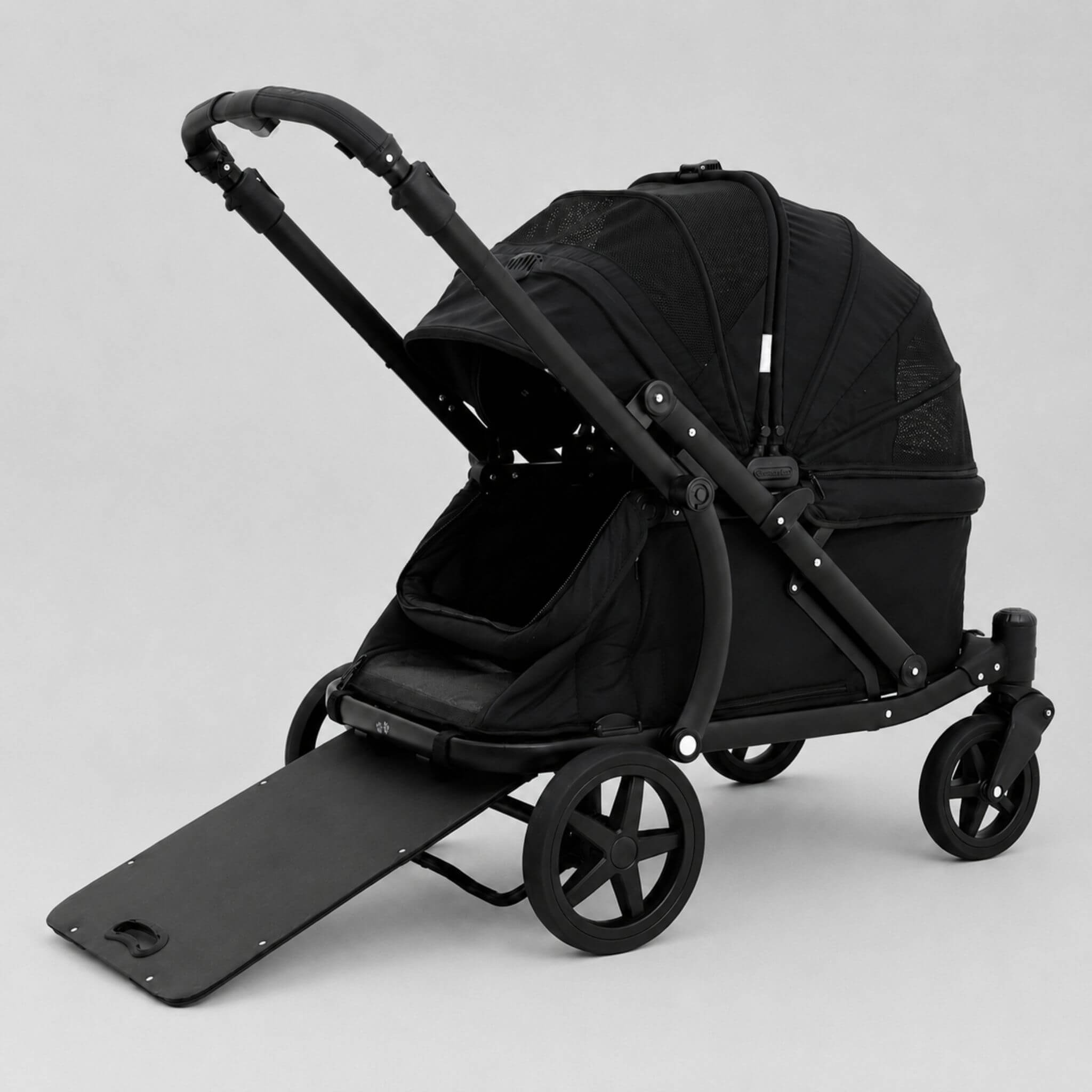 A black pet stroller with a matching black pet bed, black handlebar, and four wheels, shown on a light gray studio background with the front ramp lowered.