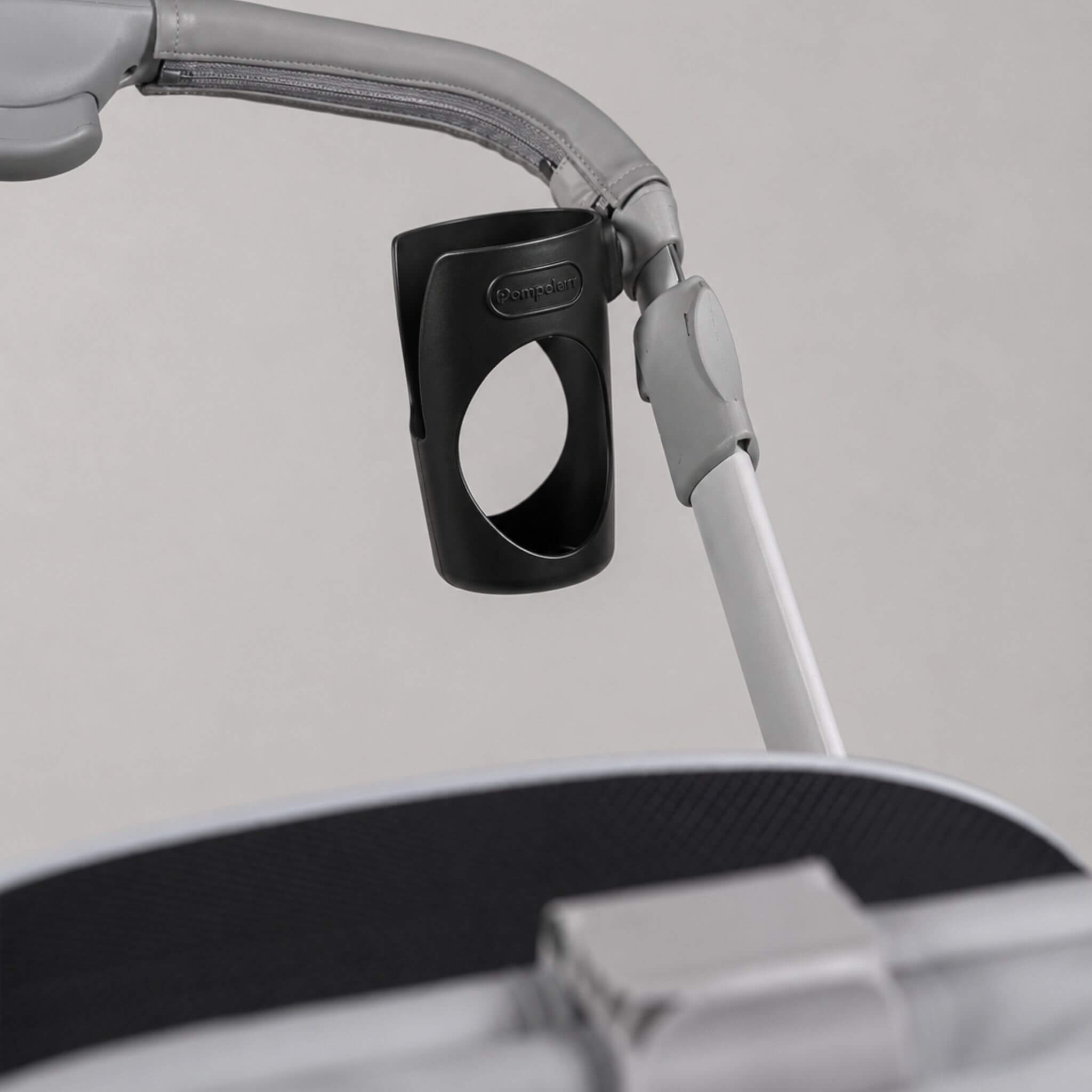 Close-up of a black DiaperClips attachment mounted to a gray and white stroller handle, with part of the stroller canopy visible in the foreground.
