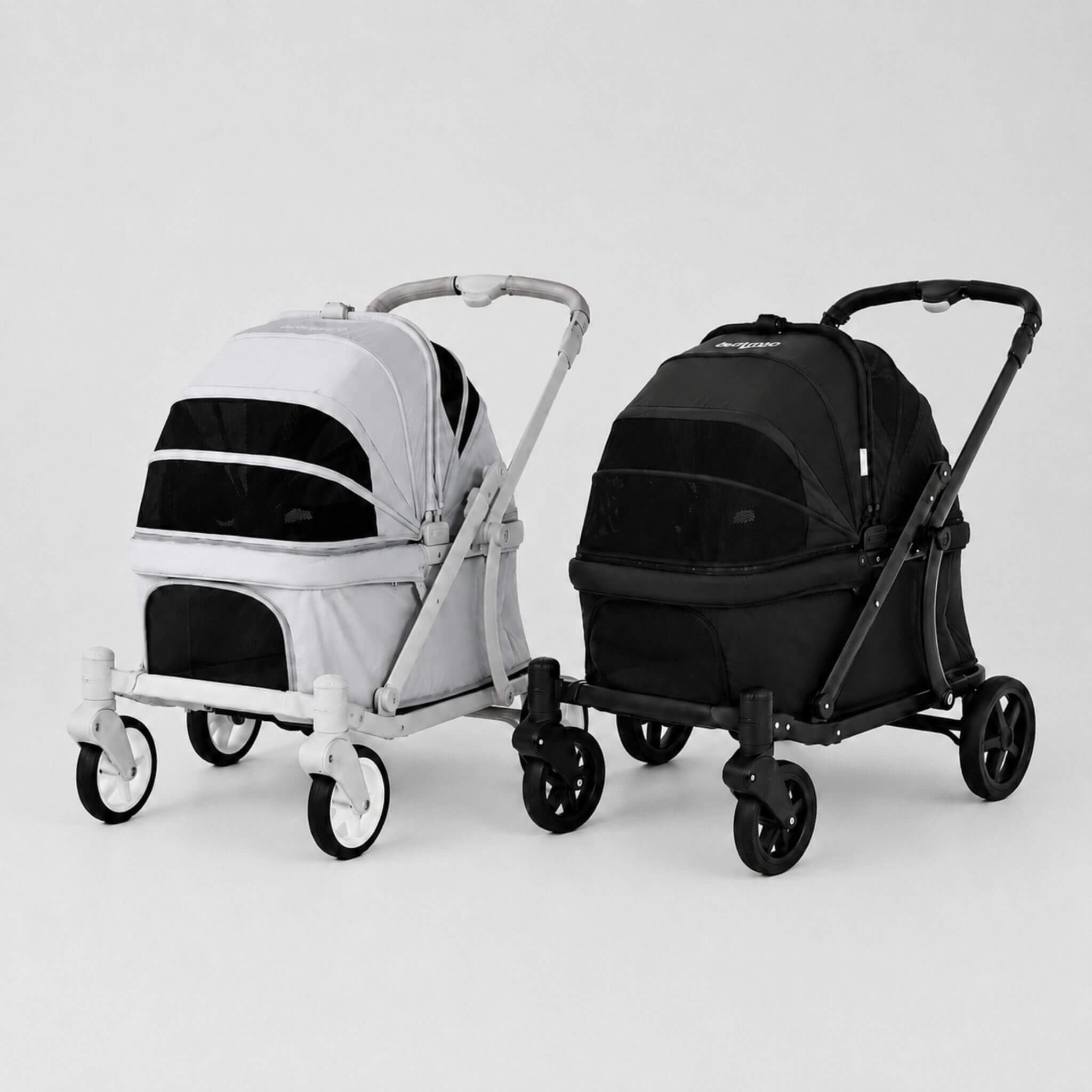 Two pet strollers shown side by side on a clean light gray studio background. The stroller on the left is light gray with black panels, and the stroller on the right is black with dark gray panels.